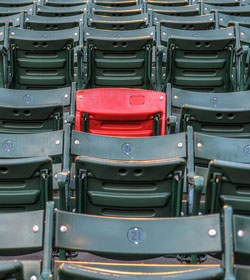 One red seat in a baseball stadium of empty green seats