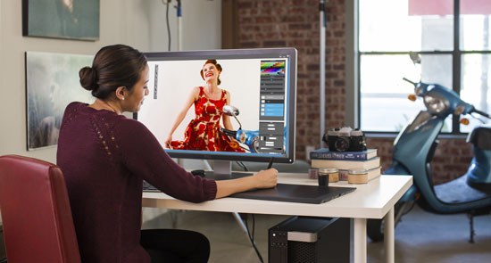 Woman at desk looking at fashion dress image on monitor