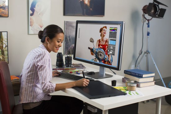Woman seated at desk in front of monitor drawing design