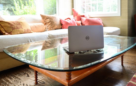 A Dell laptop sits open on a coffee table in a living room