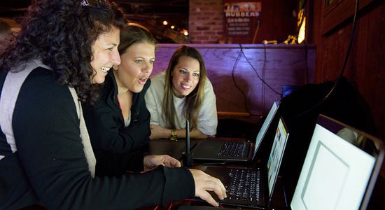  Three women look at several Dell laptops during an event