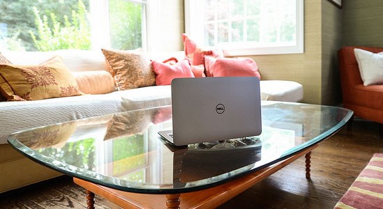 A Dell laptop in a living room illustrates technology enabling telecommuting or work from home