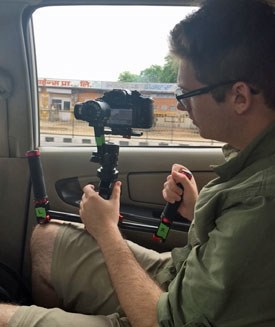 Filmmaker shooting video from inside moving vehicle