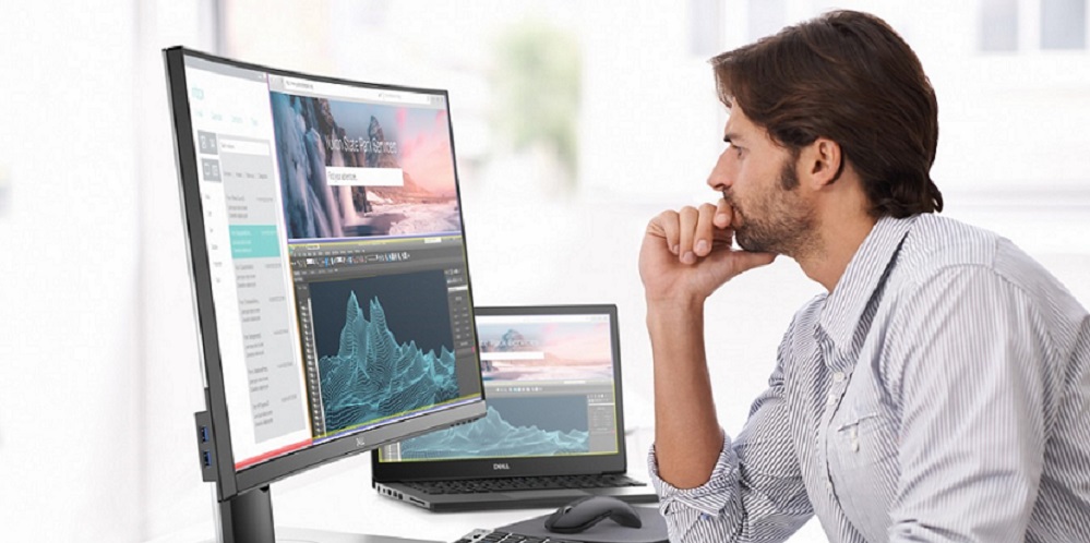 man sitting at desk looking at Dell curved monitor display