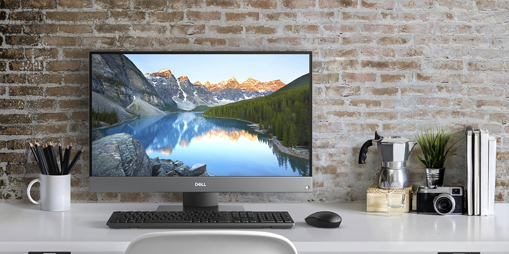 Dell Inspiron all-in-one desktop computer on white desk in front of brick wall